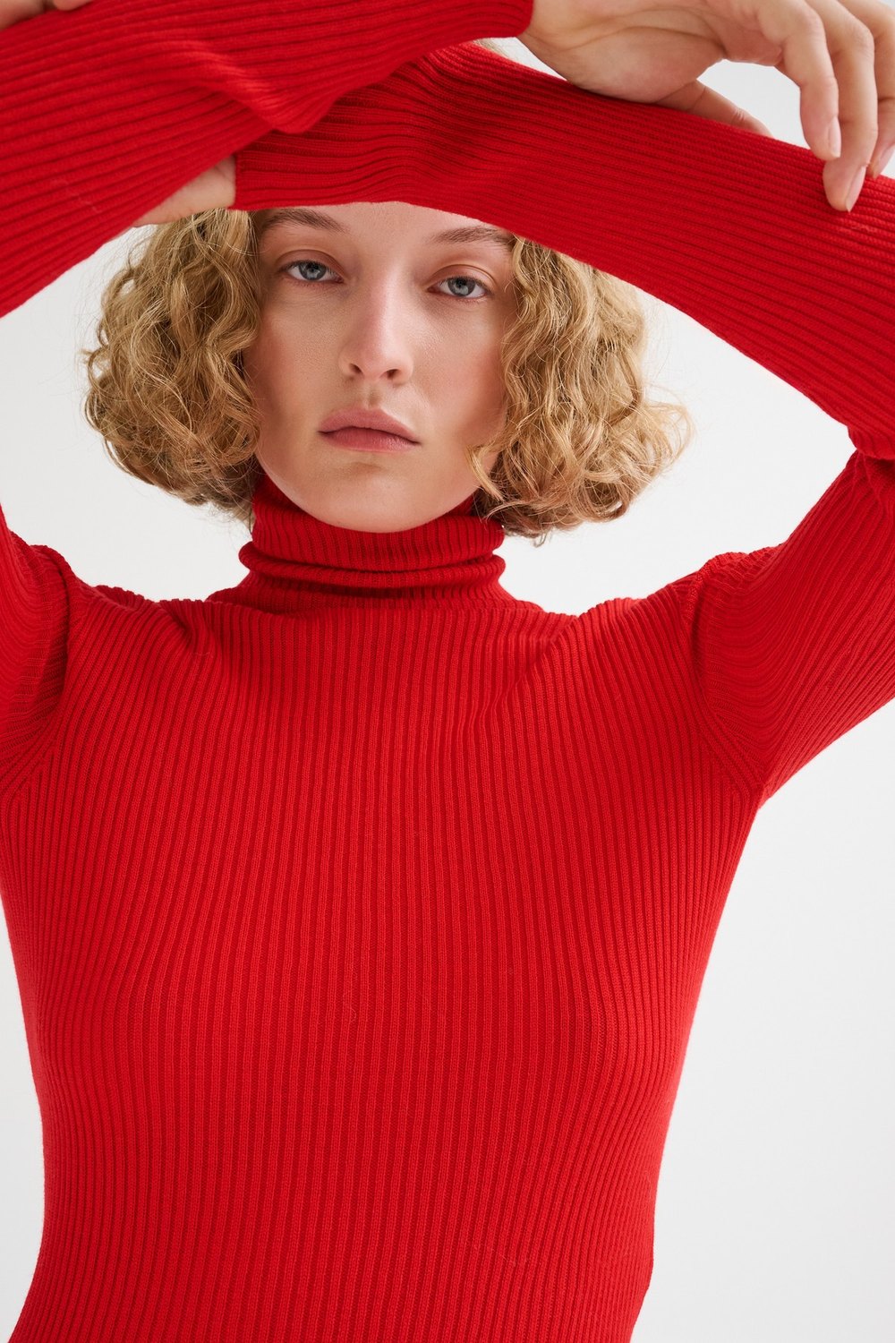 Roberto Collina — red ribbed turtleneck, hands in her hair