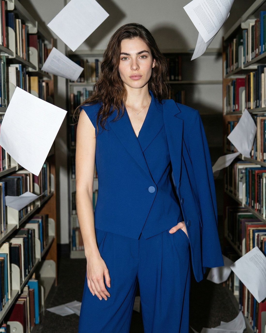 Rinascimento — AI editorial, blue suit between the shelves