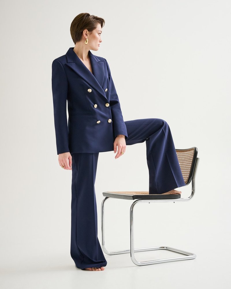 Rinascimento — editorial, navy double-breasted suit, one foot on the chair